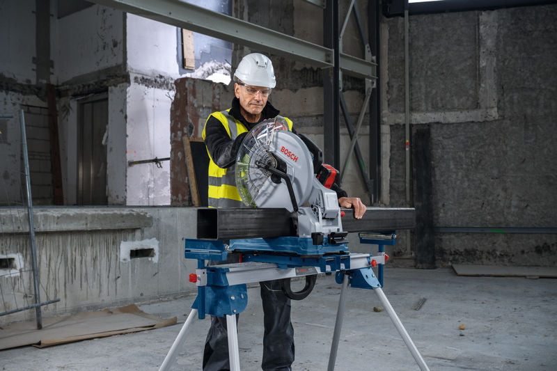 Eine Person mit Sicherheitsausrüstung bedient auf einer Baustelle eine Metalltrennsäge.