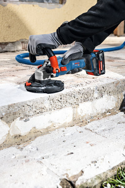 Eine Person mit Schutzausrüstung schleift Betonstufen mit einem Akku-Betonschleifer.
