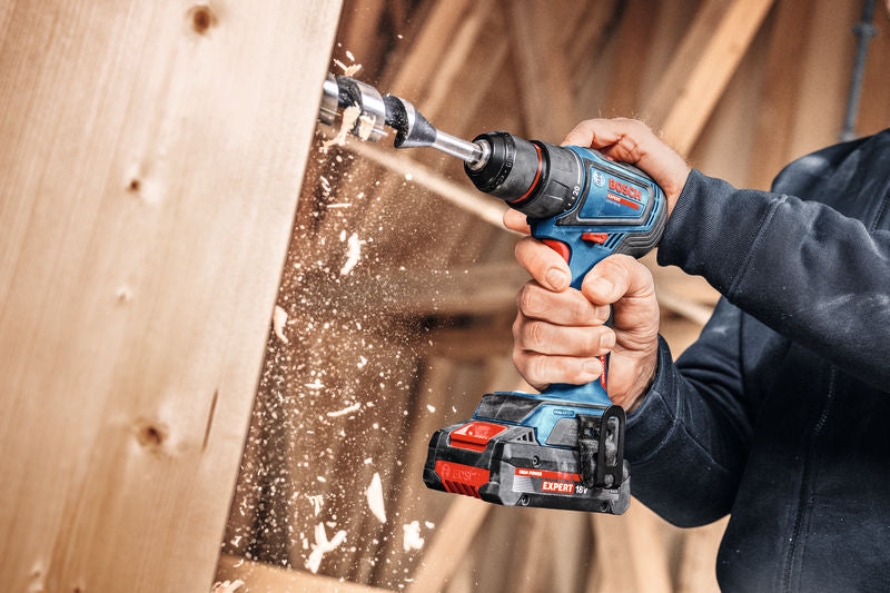 Eine Person bohrt mit einer Akkubohrmaschine ein Loch durch ein Holzbrett