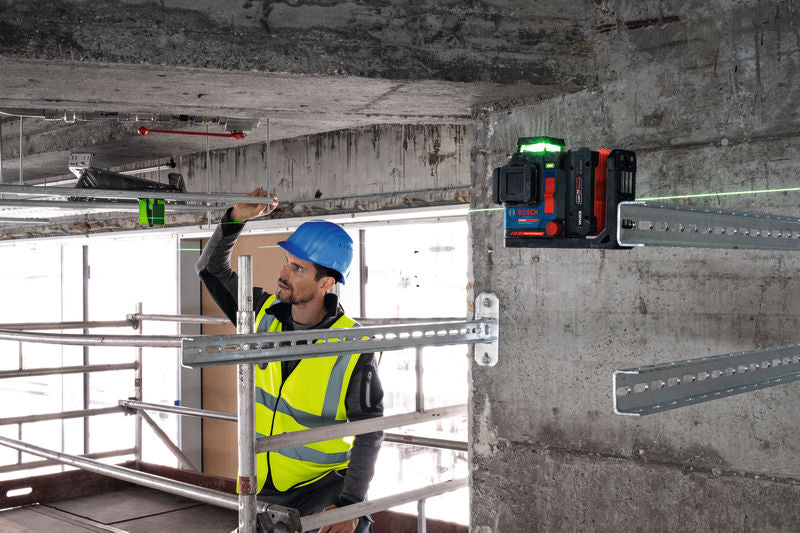 Eine Person mit Sicherheitsausrüstung richtet Metallschienen mit einem Lasernivelliergerät aus