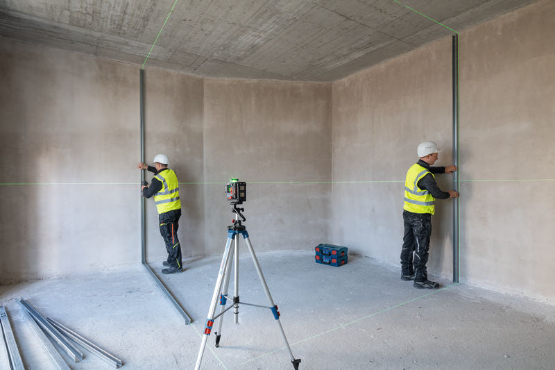 Zwei Personen mit Sicherheitsausrüstung richten Metallbolzen mit einem Lasernivelliergerät aus