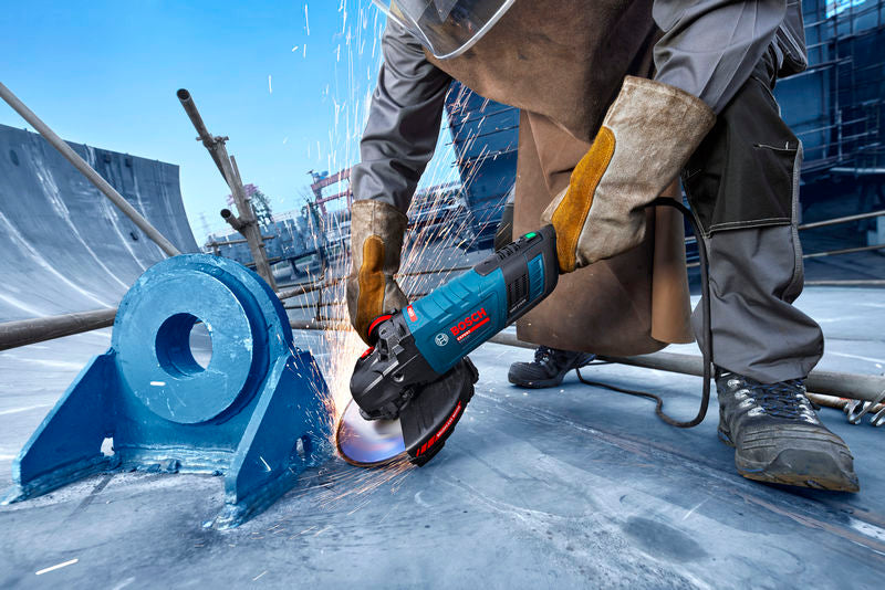 Eine Person mit Schutzausrüstung schleift Metall mit einem Elektrowerkzeug und erzeugt dabei Funken