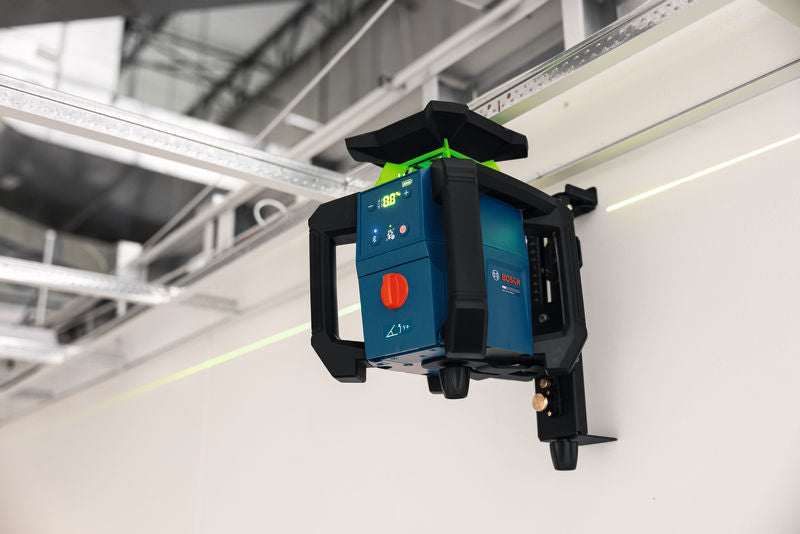 Ein Laser-Nivelliergerät projiziert eine grüne Linie an eine Wand innerhalb einer Baustelle.