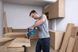 Eine Person mit Schutzausrüstung bohrt mit einem Akku-Bohrhammer in Holz.