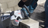 Eine Person mit Schutzausrüstung schneidet einen Betonblock mit einer Akku-Trennsäge.