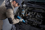 Eine Person mit Schutzausrüstung verwendet einen Akku-Ratschenschlüssel, um an einem Automotor zu arbeiten.