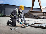 Eine Person mit Schutzausrüstung schleift im Freien Metallträger mit einem Winkelschleifer.