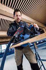 Eine Person mit Sicherheitsausrüstung verwendet eine Akku-Kreissäge zum Schneiden von Holz