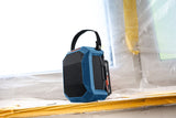 Blauer Bluetooth-Lautsprecher mit Tragegriff auf einer Fensterbank auf einer Baustelle.