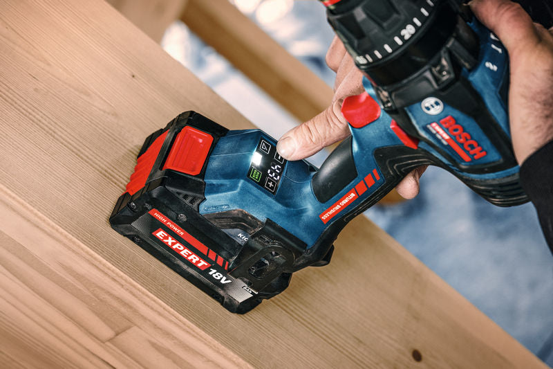 Eine Person bedient einen Akku-Schlagbohrschrauber an einem Holzbalken