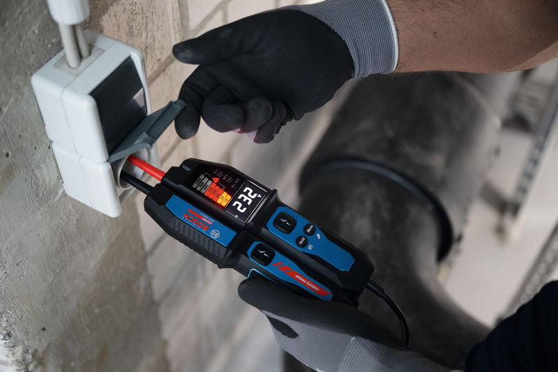 Eine Person mit Sicherheitsausrüstung verwendet einen Spannungsprüfer an elektrischen Leitungen