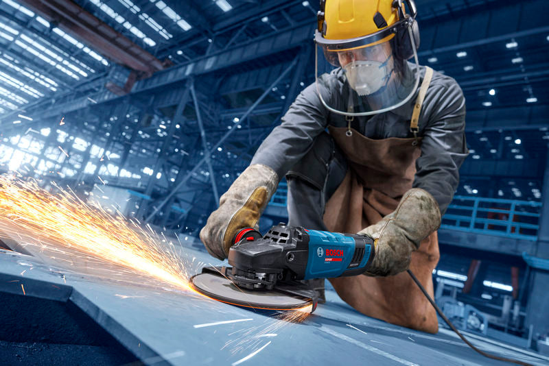Eine Person mit Schutzausrüstung schleift Metall und erzeugt dabei helle Funken