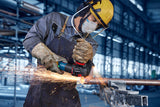 Eine Person mit Sicherheitsausrüstung schleift ein Metallrohr und erzeugt dabei helle Funken