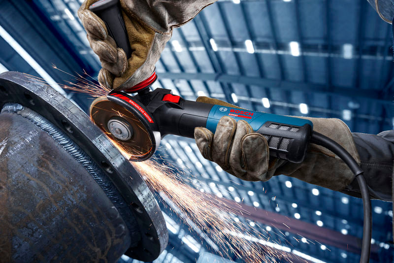 Eine Person mit Schutzausrüstung schleift Metall mit einem Winkelschleifer, wobei Funken entstehen