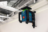 Ein Laser-Nivelliergerät projiziert eine grüne Linie an eine Wand innerhalb einer Baustelle.