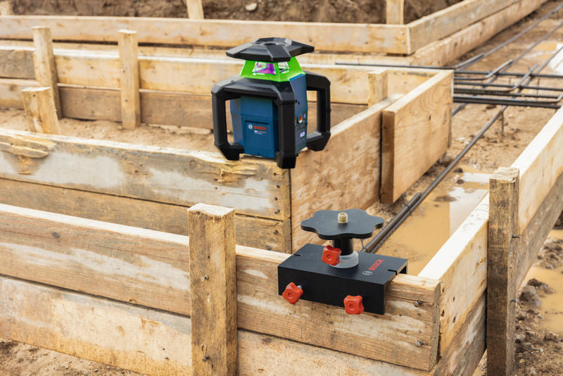 Auf einem hölzernen Fundamentrahmen an einer Baustelle aufgestelltes Laser-Nivelliergerät.