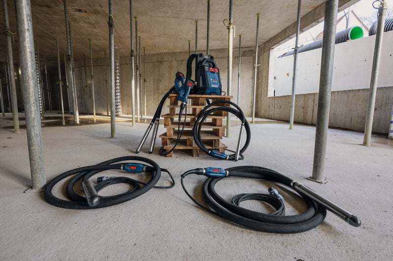 Baustelle mit zwei Betonrüttlern und einem tragbaren Netzteil auf einer Palette.